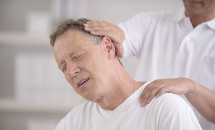 Vyras, turintis kaklo osteochondrozę, rankinio masažuotojo registratūroje